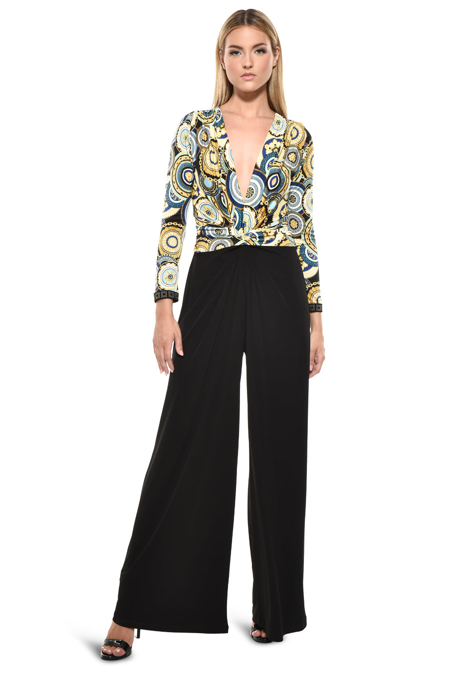 Model wearing Julian Chang Amber Jumpsuit in Contrast/Versus print, featuring a plunging V-neckline, long sleeves, and black draped pants