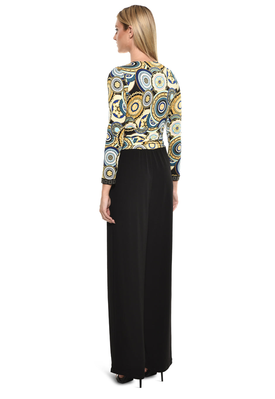 Model wearing Julian Chang Amber Jumpsuit in Contrast/Versus print, featuring a plunging V-neckline, long sleeves, and black draped pants